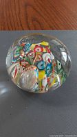 Angled view of clear glass paperweight showing multicolored millefiori interior