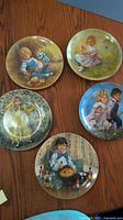 Group shot of all five Mother Goose series plates on wood surface