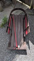 Top view of wooden sled showing slatted seat, red side rails, pull strap