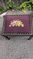 Full view of footstool showing burgundy needlepoint top with floral design and wood frame