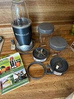 Complete NutriBullet Magic Bullet set with base, cups, blades, lids, rings and booklet on countertop