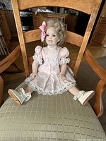 Full view of doll seated on chair showing overall appearance and outfit
