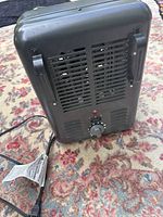 Rear view of black Intertek heater showing safety grille, thermostat knob, carry handles