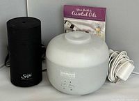 Both diffusers, power cord and booklet displayed together