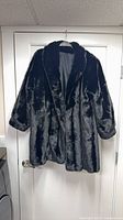 Full view of black faux fur jacket hanging to show overall style and length
