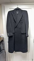 Full front view of dark charcoal wool double-breasted overcoat on hanger