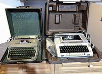 Both typewriters open in their cases showing keyboards and internal mechanisms