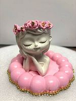 Top view showing entire pink trinket box, scalloped rim, gold beading and grey bust with pink flower crown