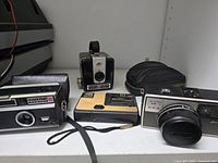 Four cameras and a zippered pouch on shelf