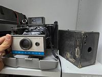 Front view of Polaroid Automatic 210 opened on tray next to black box camera
