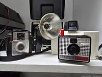 Front view of Brownie Starmite, Swinger, flash reflector and open case behind