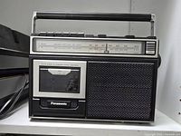 Front view showing tuner scale, cassette deck, speaker grille and handle