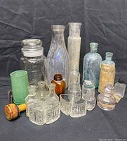 Group view of all glass bottles, jar, lamp shade and wooden handle