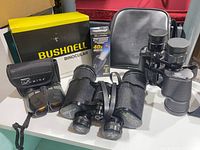 All items grouped: three binoculars, cases, boxes, TacLight