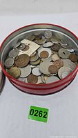 Open red tin filled with assorted coins