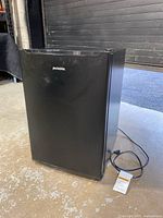 Front view of black Proctor Silex mini fridge with power cord