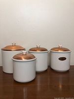 Front view of four ceramic canisters with copper lids