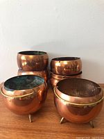 six copper planters grouped; shows hanging and footed styles