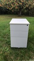 Front view of light grey 3-drawer filing cabinet on grass