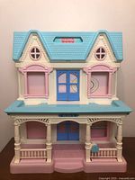 Front view of closed dollhouse showing roof, facade, porch, and mailbox