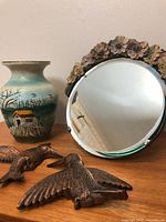 Mirror, vase, two plastic birds on wooden surface