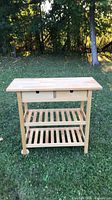 Front view of birch kitchen cart showing drawers and two slatted shelves