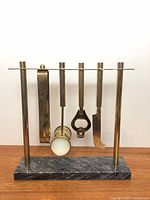 Front view of bar tool set on marble base showing all four tools hanging