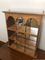 Front view showing wood frame, three arches, mirrored back and shelving