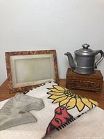 Group shot of all five items: pewter teapot on carved box, alabaster frame, cement horse head, printed feed bag