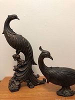 Two resin peacock statues on tabletop