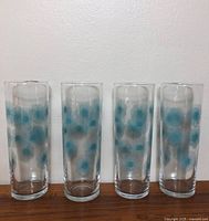 Four matching tall glasses upright on wood surface