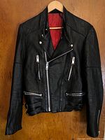 Front view of Ortov black leather motorcycle jacket on hanger