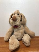 Full view of plush Wrinkles dog hand puppet seated upright