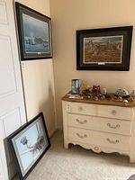 Overall view of three framed prints: two hung, one leaning