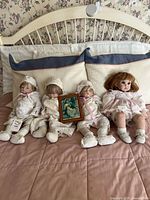 Overview of four dolls and framed photo on bed