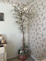 Full view of artificial flowering tree in corner showing height and blossoms