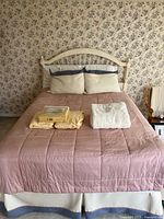 Full view of bed with headboard, mattress, comforter, pillows, extra linens