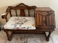 Overall view of wooden bench with attached cabinet and cushion
