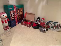 Overview of all items grouped in corner: boxed animated figures, plush figures, tree skirt, plaques, ornament box