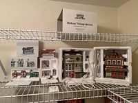 Overall lot on shelf: three building boxes opened showing buildings, one open accessory set showing figurines, boxed accessory items