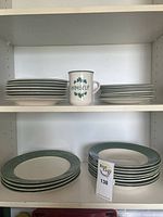 Stacks of small plates, bowls, saucers, and mug on shelf