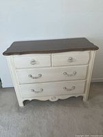 Front view of dresser showing cream body, brown top, hardware, scalloped apron
