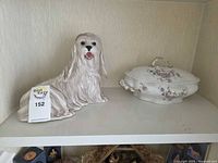 Dog figurine left, covered tureen right on shelf