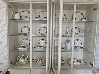 Full cabinet view showing majority of Royal Albert dinnerware and glassware