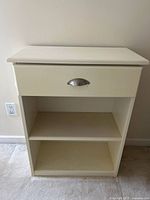 Front view of cream wooden shelf unit showing drawer and two shelves