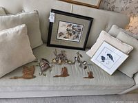 Overview of all framed prints, wood carvings and metal pieces on couch
