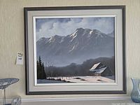 Framed winter mountain landscape oil painting on shelf