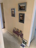 Group shot of framed art pieces leaning and hanging on hallway wall