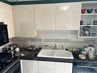 Overview of countertop showing pots, plates, sink and assorted mugs