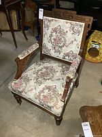 Front view of Eastlake armchair showing carved crest, floral upholstery, and overall structure